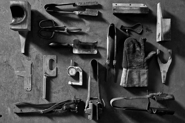 A photo of the very basic tools used by glassmakers, including scissors, a  compass, and wooden paddle.