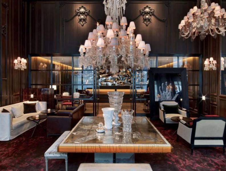 A table with a beautiful chandelier hanging above it int eh Lobby at Baccarat New York