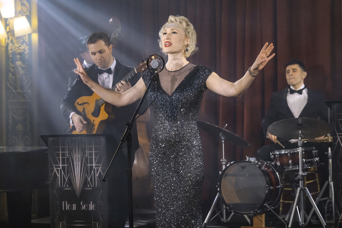 A singer dressed in an elegant sparkling dress performs for a crowd