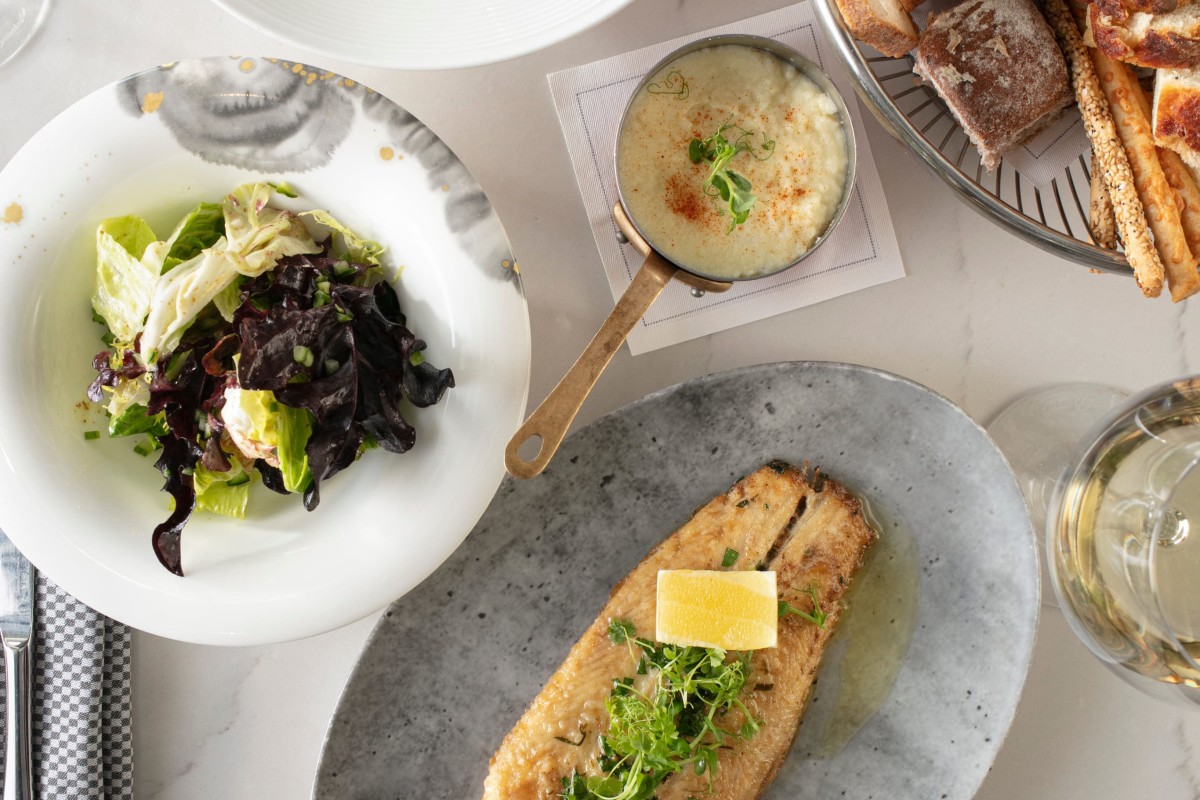 A spread of different in-room dining options such as fish, salad, bread, and risotto