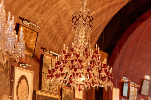 Man and women walking  hand in hand under an ornate chandelier in a bar