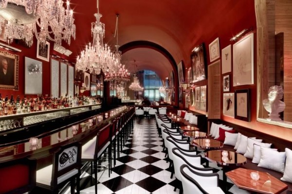 A beautiful Bar at Baccarat NYC with black and white checkered tiled floors and gorgeous chandeliers above the bar