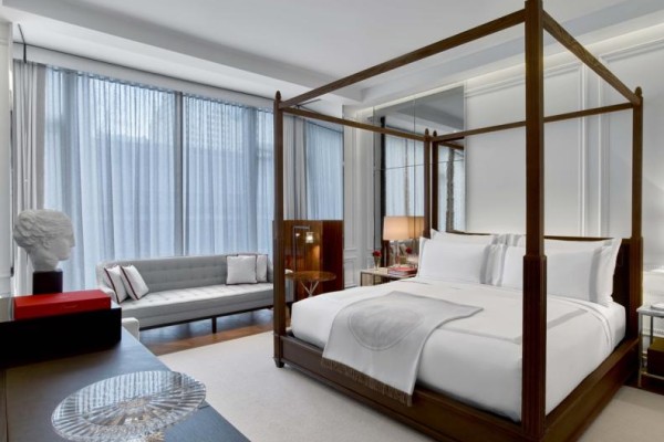 Elegant Classic King Suite with four-post bed, tufted bench sofa, sheer curtains, and hardwood floors with area rug