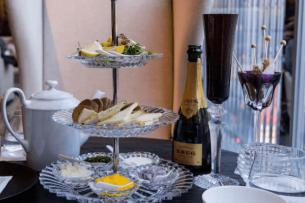 Pastries and sweets displayed on a 3 tier Baccarat glass serving tower, complete with a bottle of champagne
