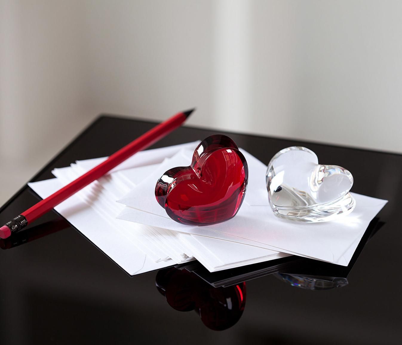 Picture of a pen and 2 glass hearts resting on paper