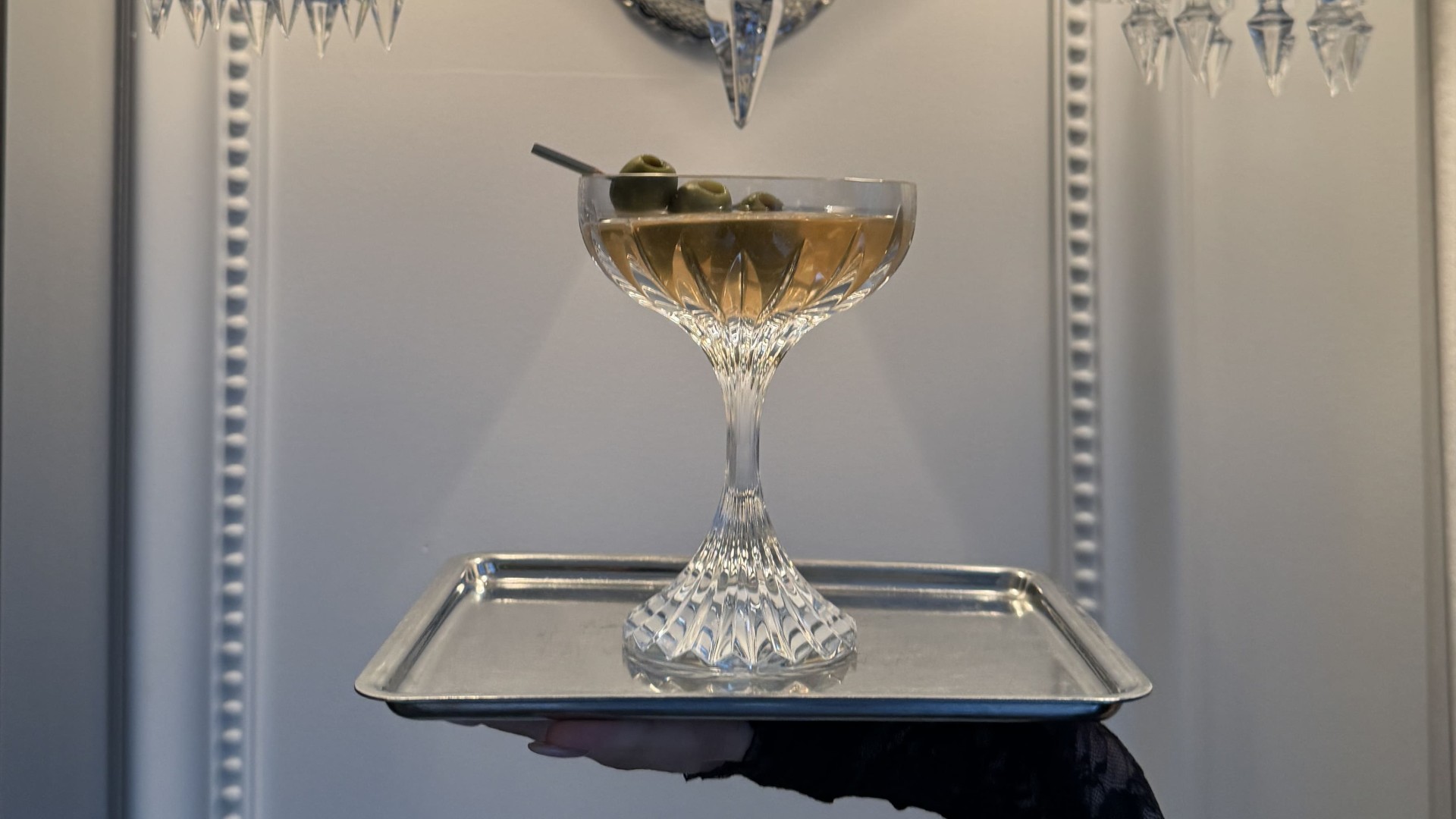A hand holding a glass on a platter