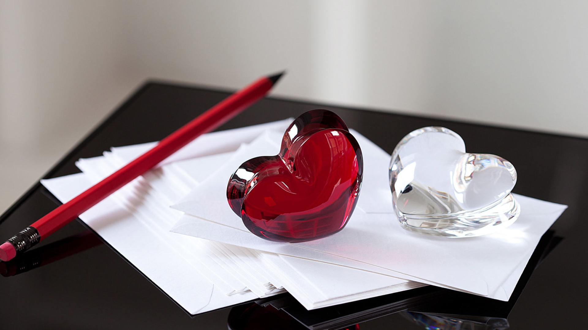 Picture of a pen and 2 glass hearts resting on paper