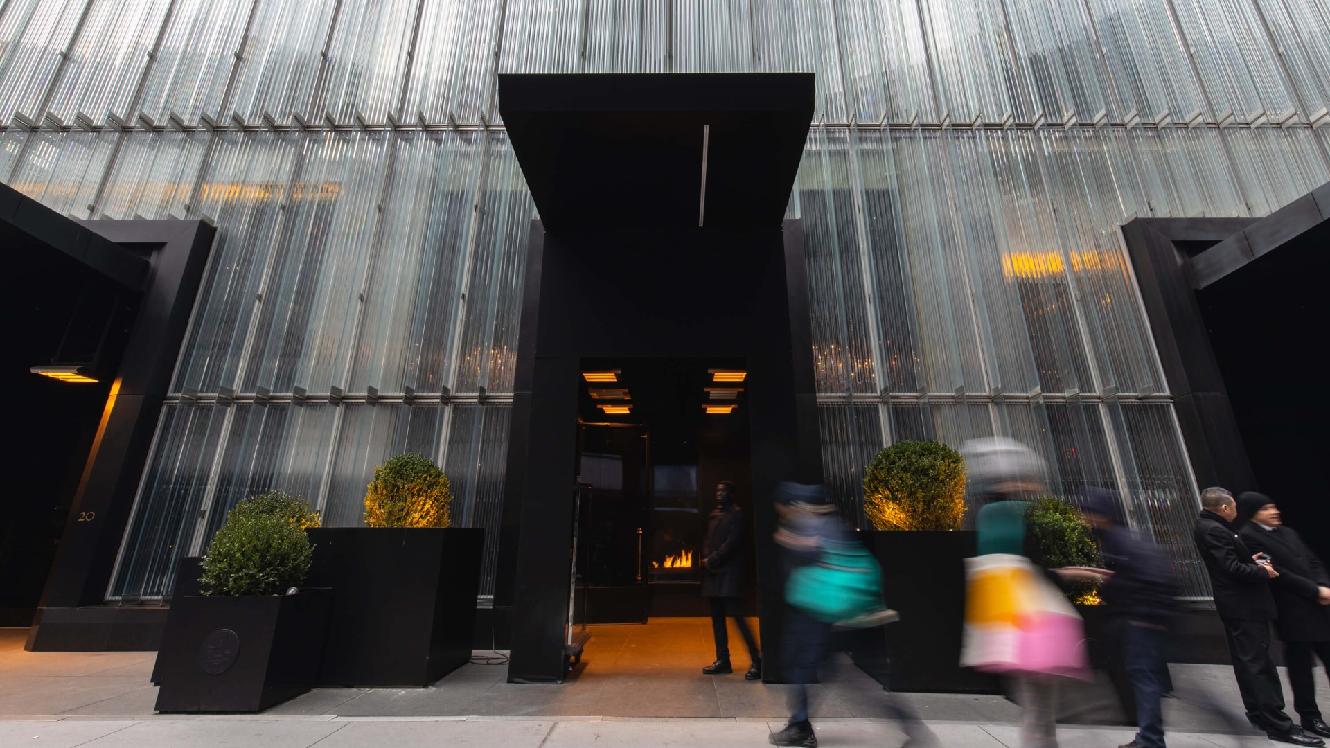 People walking by a modern building featuring large glass walls