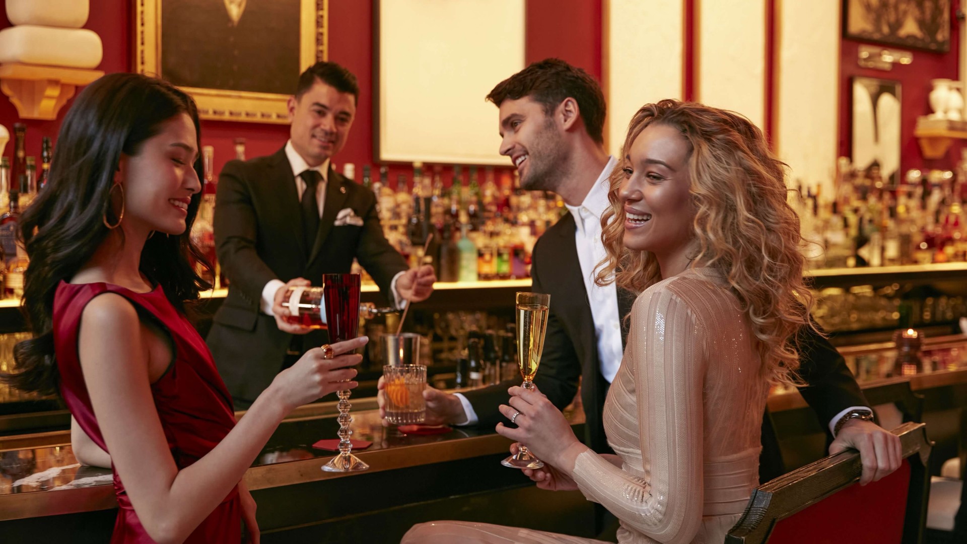 Two women enjoying drinks together at a lively bar, chatting and laughing