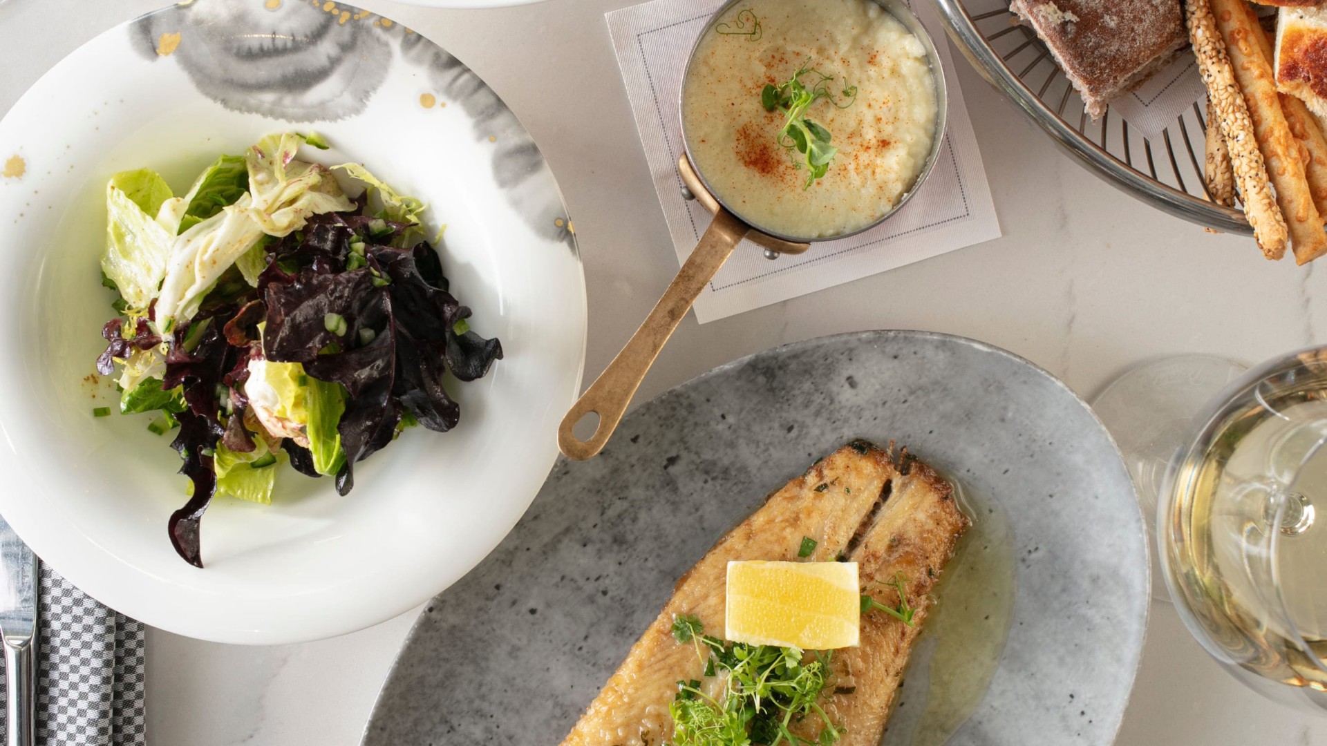 A spread of different in-room dining options such as fish, salad, bread, and risotto