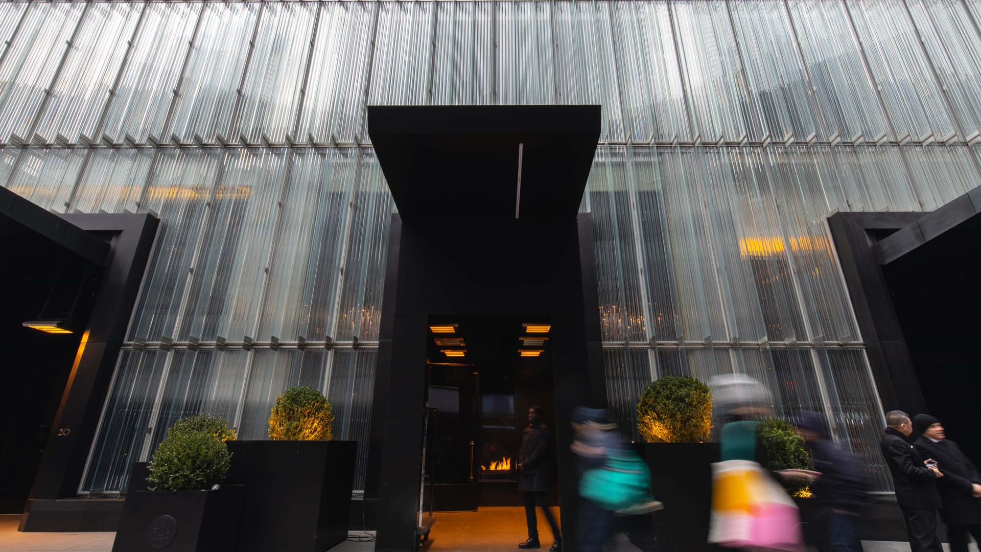 People walking by a modern building featuring large glass walls