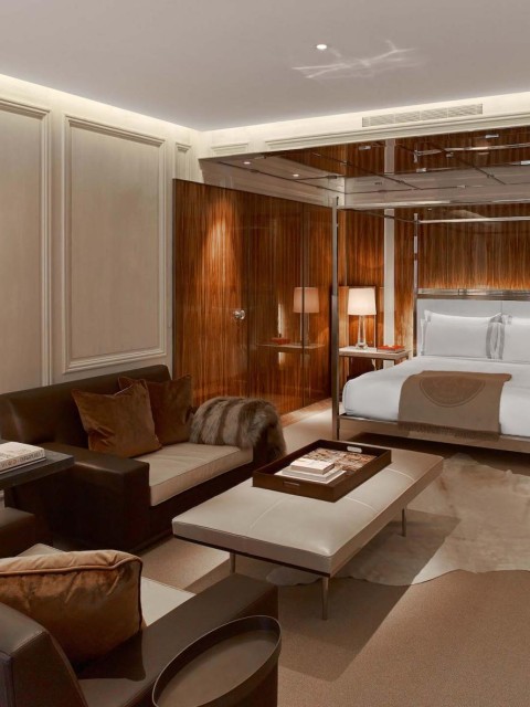 A cozy bedroom featuring a bed, a couch, a table, and a lamp, creating a warm and inviting atmosphere.