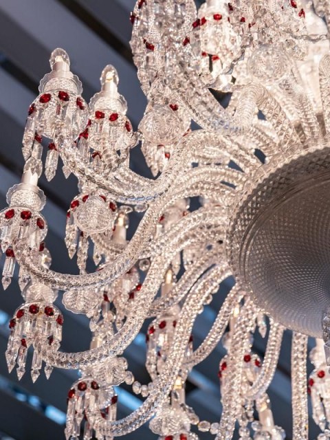 A large crystal chandelier adorned with red and white beads, reflecting light elegantly in a spacious room.