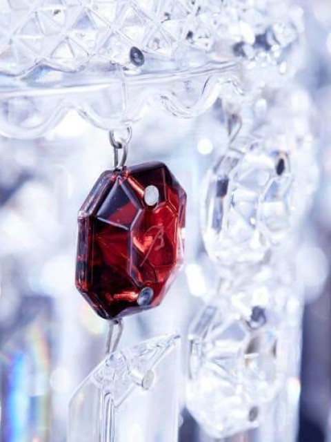 A red crystal chandelier adorned with a prominent red stone, showcasing intricate design and elegance.