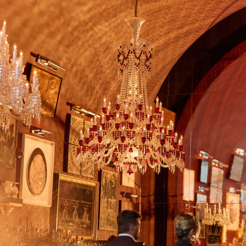 Man and women walking  hand in hand under an ornate chandelier in a bar
