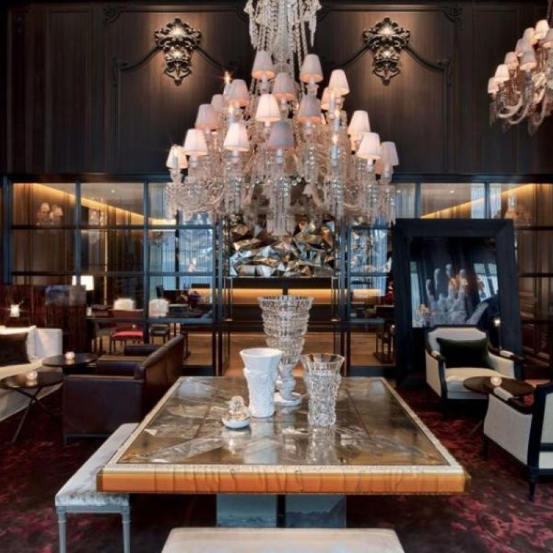 A table with a beautiful chandelier hanging above it int eh Lobby at Baccarat New York
