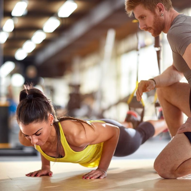 A man and woman performing push-ups on gym mats, demonstrating strength and fitness in a workout setting
