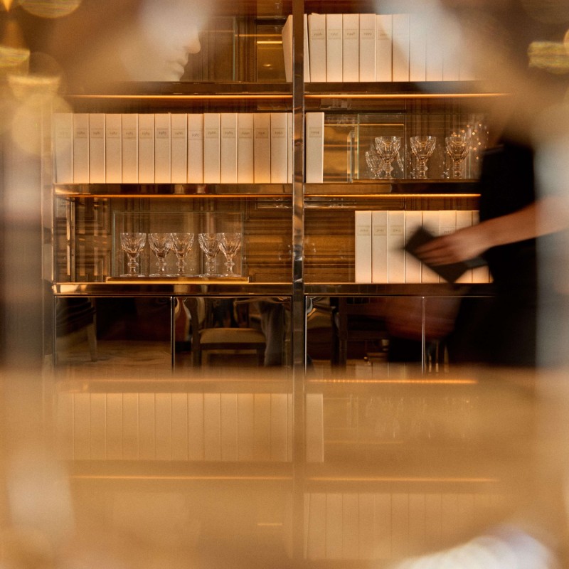 Blurry image of a bar featuring several wine glasses on the counter, creating a warm, inviting atmosphere.