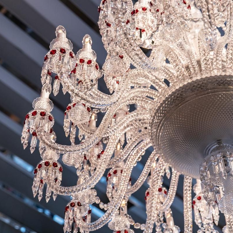 A large crystal chandelier adorned with red and white beads, reflecting light elegantly in a spacious room.
