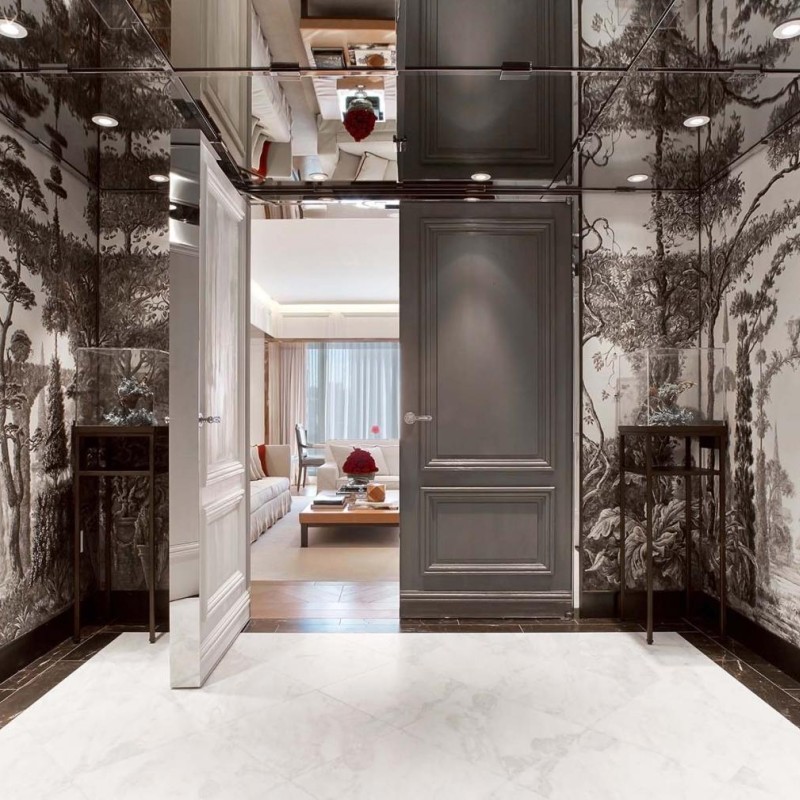 A hallway featuring a large mirror on one wall and a striking black and white mural on the opposite wall.