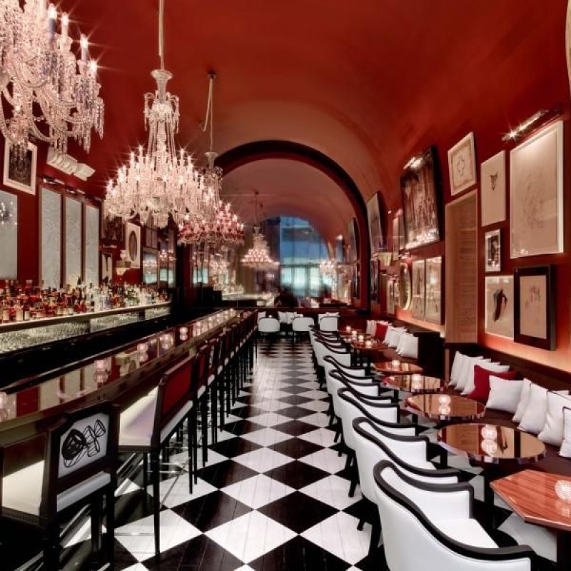 Un precioso bar en el Baccarat de Nueva York, con suelos de baldosas a cuadros blancos y negros y unas magníficas lámparas de araña en el techo. the bar