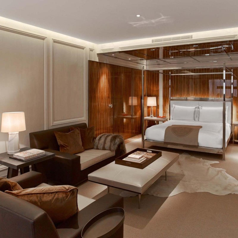 A cozy bedroom featuring a bed, a couch, a table, and a lamp, creating a warm and inviting atmosphere.